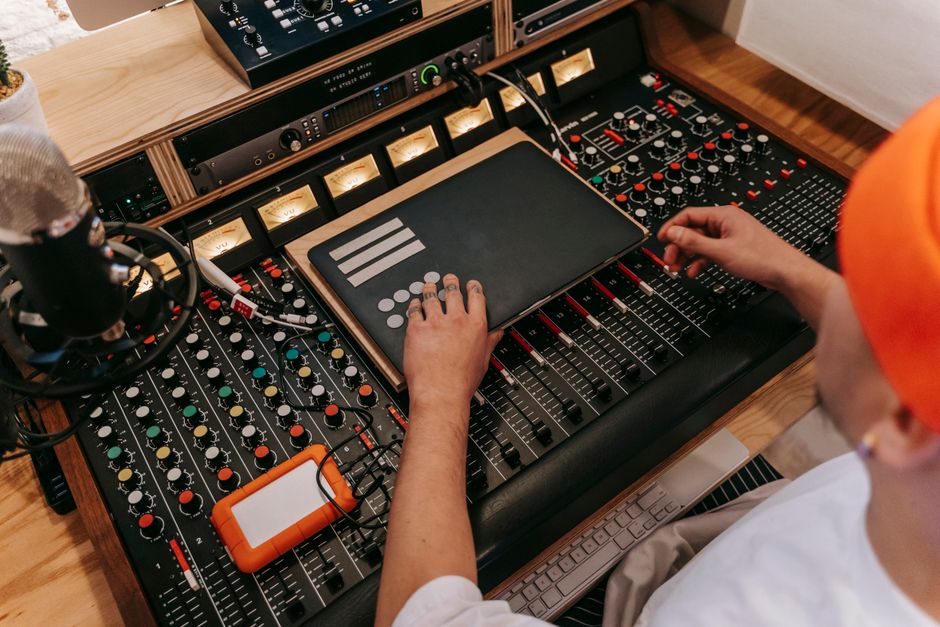 High angle view of a DJ using sound mixer and technology equipment in a studio setting.