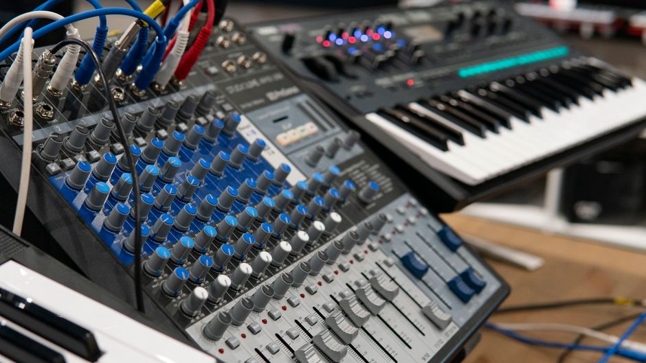 Detailed view of an audio mixer panel and connected synthesizer with colorful cables.